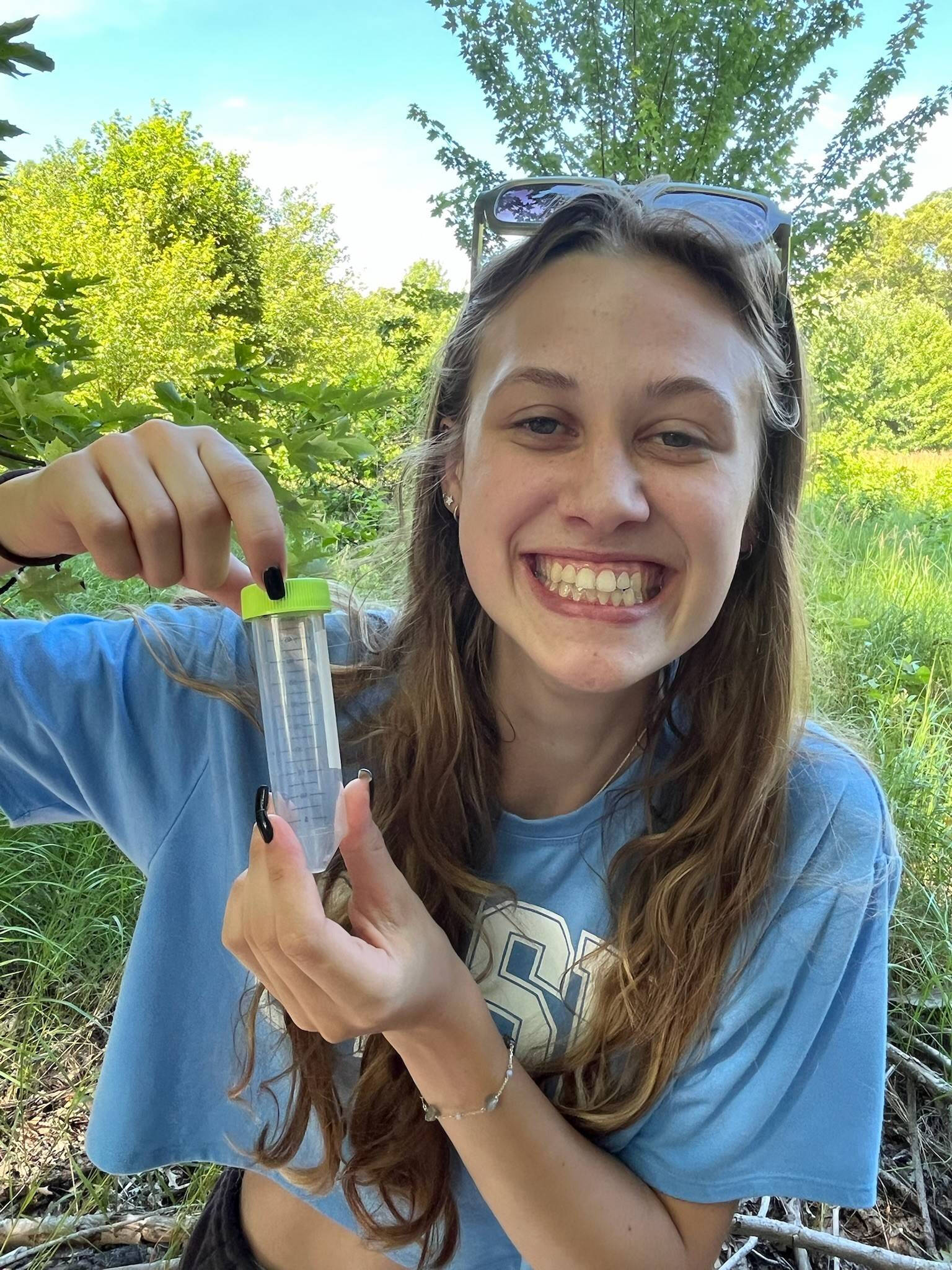 Student holding tick in container.
